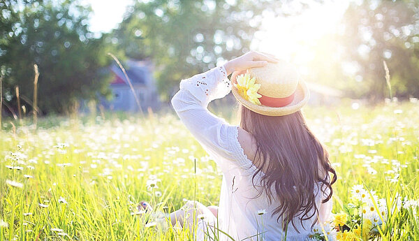Bild einer Frau die auf einer Wiese sitzt